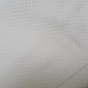 May include: White fabric with a textured, woven pattern. The fabric has a subtle sheen and a smooth, soft feel.
