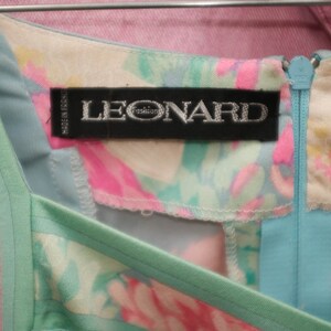 May include: A light blue and pink floral dress with a green trim and a zipper closure. The dress has a label that reads "LEONARD Paris".