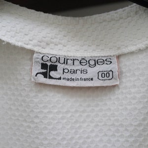 May include: White cotton shirt with a white label that reads "Courr&egrave;ges Paris made in France 00".