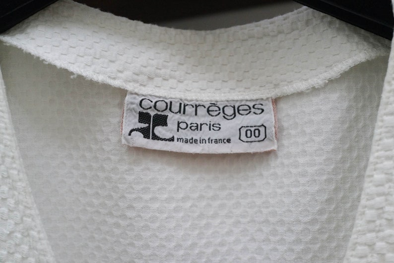 May include: White cotton shirt with a white label that reads "Courr&egrave;ges Paris made in France 00".