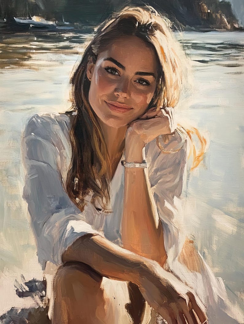 May include: A woman with long blonde hair sits on a sandy beach, wearing a white shirt and looking at the camera with a smile. The background is a blurry image of a body of water and a rocky shore.