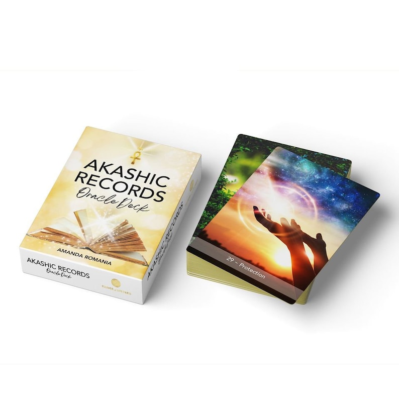 Pu&ograve; includere: Mazzo di carte oracle Akaschic Records di Amanda Romania. La scatola presenta un simbolo Ankh dorato e un libro aperto con un bagliore dorato. La carta mostra un paio di mani che si alzano verso una luce brillante nel cielo.