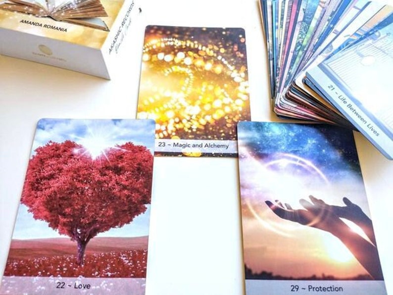 Pu&ograve; includere: Quattro carte di oracoli con immagini e testo colorati. Le carte sono intitolate "Magia e Alchimia", "Vita tra le vite", "Amore" e "Protezione".
