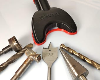 May include: A black and red drill bit holder with the text "DRILL &" printed on it. Five drill bits are arranged around the holder, including a 32mm drill bit.