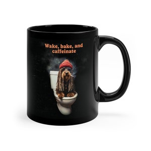 May include: Black coffee mug with a white toilet and a dog wearing a red hat and sitting on the toilet. The text on the mug reads "Wake, bake, and caffeinate."