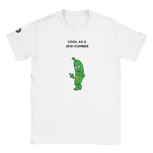 May include: White t-shirt with the text "COOL AS A JEW-CUMBER" above a cartoon pickle character. The pickle is green with a gold necklace and is pointing with its left hand. The t-shirt has a crew neck and short sleeves.