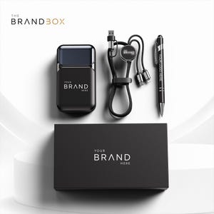 Può includere: Una scatola regalo rettangolare nera etichettata THE BRANDBOX contenente un power bank nero, un cavo di ricarica multi-connettore nero con un disco logo circolare e una penna a sfera nera con il testo YOUR LOGO HERE stampato sul lato.