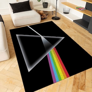 Puede incluir: Alfombra negra y blanca con un diseño de prisma de arcoíris. La alfombra presenta un gran triángulo con un rayo de luz de arcoíris que emana de él.