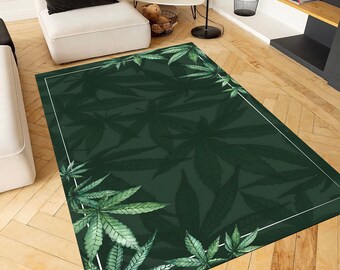 May include: A green area rug with a white border featuring a repeating pattern of large green leaves. The rug has a dark green background and the leaves are a lighter shade of green.