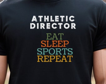 May include: A black t-shirt with the text "Athletic Director" and the words "Eat, Sleep, Sports, Repeat" in colorful vintage-style lettering.