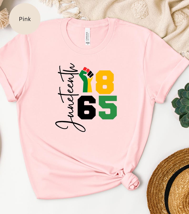Puede incluir: Camiseta rosa con el texto "Juneteenth 1865" y un pu&ntilde;o levantado en rojo, negro y verde.