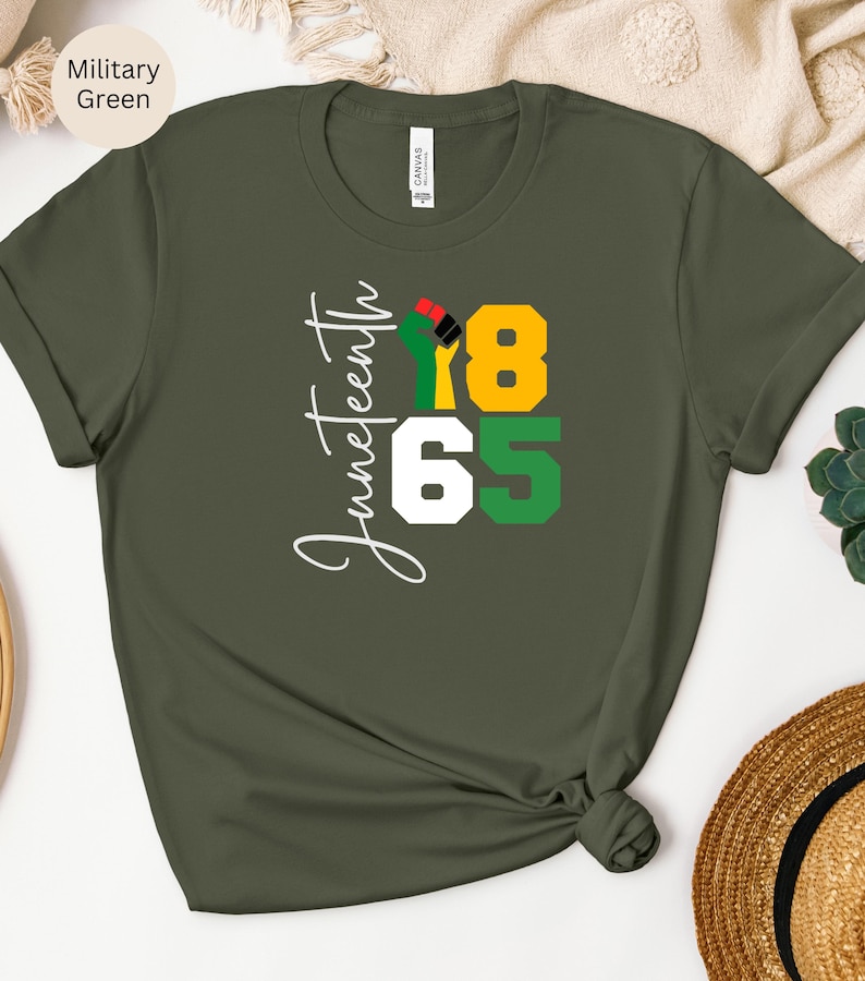 Puede incluir: Una camiseta verde con el texto "Juneteenth 1865" en blanco. Un pu&ntilde;o negro con acentos rojos, amarillos y verdes est&aacute; en el centro del dise&ntilde;o.