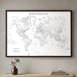 白い額縁に入ったプッシュピン式世界地図 – ミニマルな旅行壁飾り