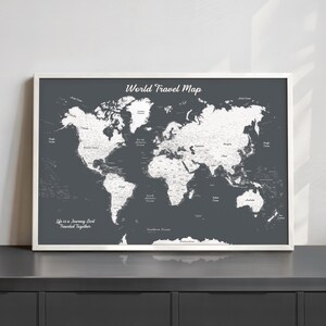 May include: A framed world travel map in a white frame. The map is a dark gray color with white continents and country outlines. The text "World Travel Map" is at the top, and "Life is a Journey Best Traveled Together" is at the bottom.