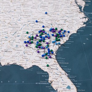 Puede incluir: Un mapa del sureste de los Estados Unidos con numerosas chinchetas. Las chinchetas son de varios colores, incluyendo azul, verde y morado. El mapa muestra estados como Georgia y Florida.