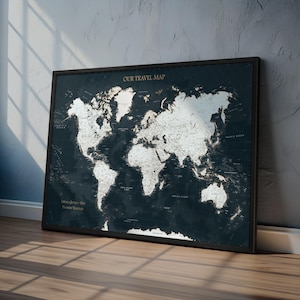 May include: A framed world map with a dark blue background and white continents. The words "OUR TRAVEL MAP" are at the top. The map is leaning against a wall. The text "Life is a Journey, Not a Destination" is at the bottom.