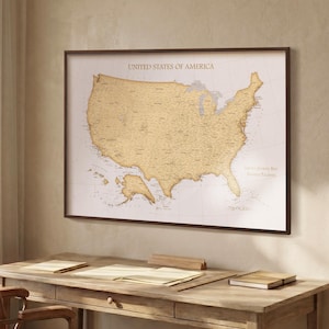 May include: A framed wall map of the United States of America with a gold-toned landmass against a white background. The map features the text UNITED STATES OF AMERICA at the top and LIFE IS A JOURNEY BUT TRAVELLED TOGETHER on the right side.