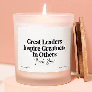 以下が含まれることがあります： 木製の蓋が付いた、点灯したすりガラスのキャンドル。キャンドルには「Great Leaders Inspire Greatness In Others Thank You！」というテキストが書かれた白いラベルが付いています。キャンドルは226gです。
