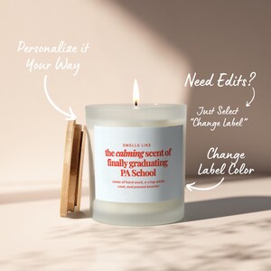 May include: A lit, frosted glass candle with a wooden lid. The candle's label reads "the calming scent of finally graduating PA School." Text on the label also mentions "notes of hard work, a crisp white coat, and passed boards!"