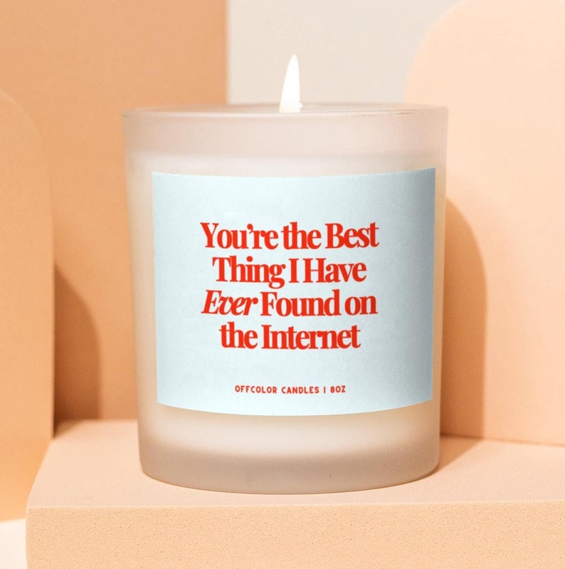 May include: A white frosted glass candle with a blue label that reads "You're the Best Thing I Have Ever Found on the Internet" and "OFFCOLOR CANDLES | 8OZ".