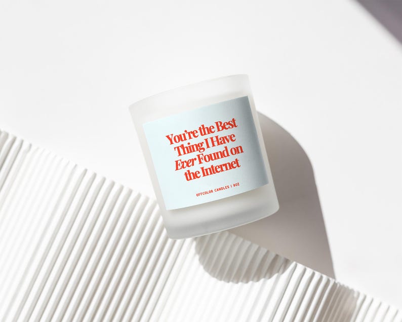 May include: White candle with a red label that reads "You're the best thing I have ever found on the internet." The label also includes the text "Offcolor Candles | 8oz."
