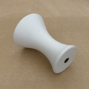 May include: White ceramic knob with a rounded top and a flat bottom. The knob has a small hole in the center of the bottom.
