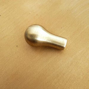 May include: A solid brass cabinet knob with a rounded top and a cylindrical base. The knob has a smooth, polished finish and is designed for easy grip and installation. This hardware is suitable for drawers and doors.