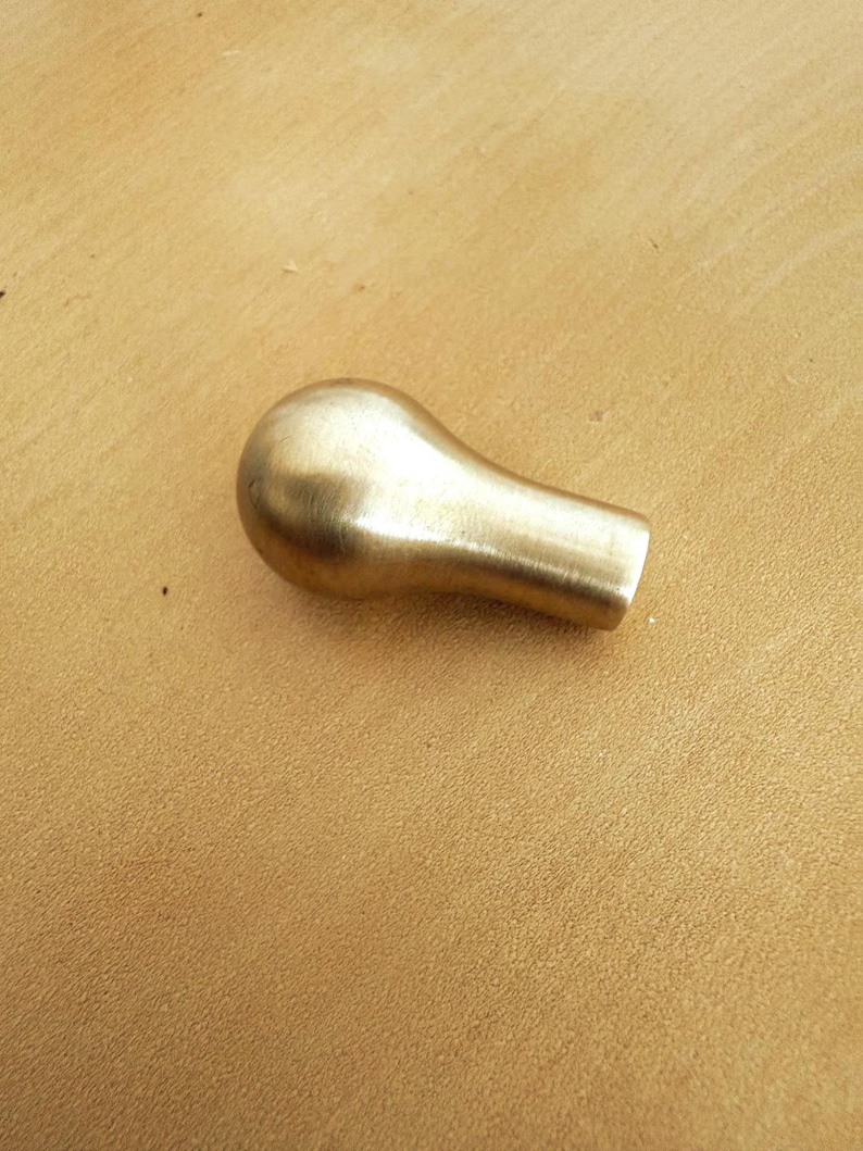 May include: A solid brass cabinet knob with a rounded top and a cylindrical base. The knob has a smooth, polished finish and is designed for easy grip and installation. This hardware is suitable for drawers and doors.