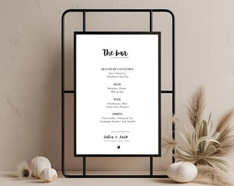 May include: A black metal framed sign with a white background. The sign reads "The bar" in cursive, followed by a list of drinks: cocktails, beer, wine, and spirits. The names "Julia & Jack" and the date are at the bottom.