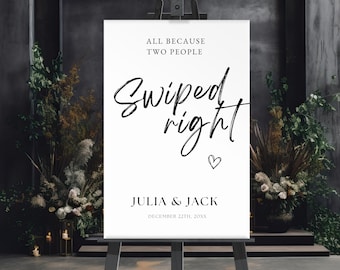 Puede incluir: Un letrero de bienvenida de boda blanco sobre un caballete de madera. El letrero dice "All because two people swiped right" con los nombres Julia & Jack y la fecha de la boda. El letrero está rodeado de arreglos florales.
