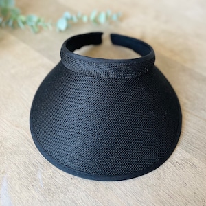 May include: A black sun visor with a wide brim and a black elastic band.
