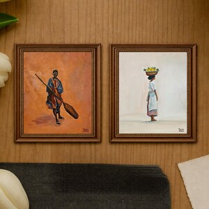 May include: Two framed paintings. The left painting depicts a person holding a large oar, set against an orange background. The right painting shows a person carrying a basket of fruit on their head, set against a white background. Both paintings are in ornate brown frames.