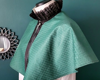 May include: A green and black cape with a black lace collar. The cape has a zipper closure and a zig-zag pattern.