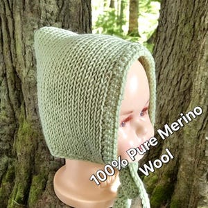 Puede incluir: Un gorro de bebé de punto verde con una larga corbata. El gorro está hecho de 100% lana merino pura.