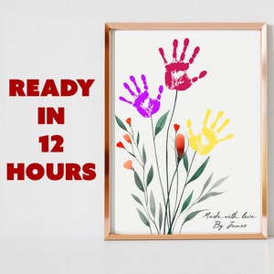 Puede incluir: Una impresión enmarcada con flores de huellas de manos de colores. La obra de arte incluye huellas de manos moradas, rojas y amarillas con tallos y hojas verdes. El texto "Made with love By James" está en la parte inferior. Las palabras "READY IN 12 HOURS" están a la izquierda.