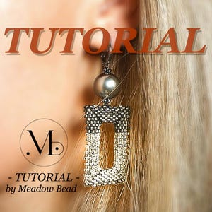May include: A close-up of a silver and white beaded earring with a black bead at the top. The earring is hanging from a person's ear. The text "TUTORIAL - by Meadow Bead" is visible below the earring.