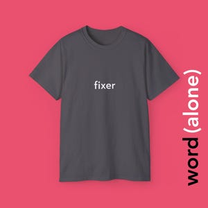 May include: A dark gray t-shirt with the word "fixer" printed in white on the front.