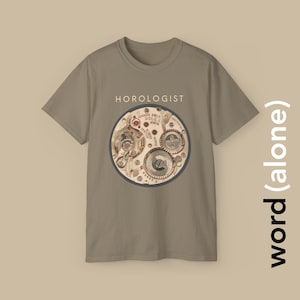 Può includere: T-shirt color cachi con grafica circolare di meccanismi di orologi, ingranaggi e altri componenti. La parola "HOROLOGIST" è stampata sopra la grafica. Il design include il marchio "ROLEX". La maglietta ha maniche corte e girocollo.
