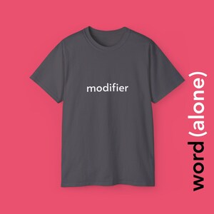 Peut inclure: Un t-shirt gris foncé avec le mot "modifier" imprimé en blanc sur le devant.
