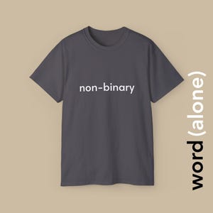 Könnte beinhalten: Ein dunkelgraues T-Shirt mit dem Text "non-binary" in weiß auf der Vorderseite.