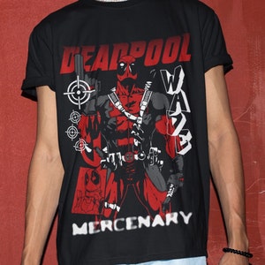 Puede incluir: Camiseta negra con una ilustraci&oacute;n roja y negra de Deadpool, un personaje de superh&eacute;roe, sosteniendo un arma. El texto "DEADPOOL" y "MERCENARY" est&aacute; impreso en la camiseta en blanco.