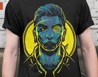 May include: A black t-shirt with a graphic of a blue and yellow stylized illustration of a person with a robotic eye. The person is wearing a black jacket and has a black and white design on their neck.