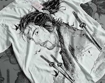 Op de afbeelding: Zwart-witte grafische t-shirt met een samurai-krijger met een zwaard. Het ontwerp is gedetailleerd en ingewikkeld, met de nadruk op het gezicht en haar van de krijger.