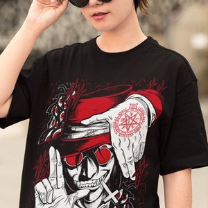 May include: Black t-shirt with a red and white illustration of a vampire with a top hat and a pentagram on his hand. The vampire is wearing a red tie and has a cross on his chest. The background is black with red and white details.