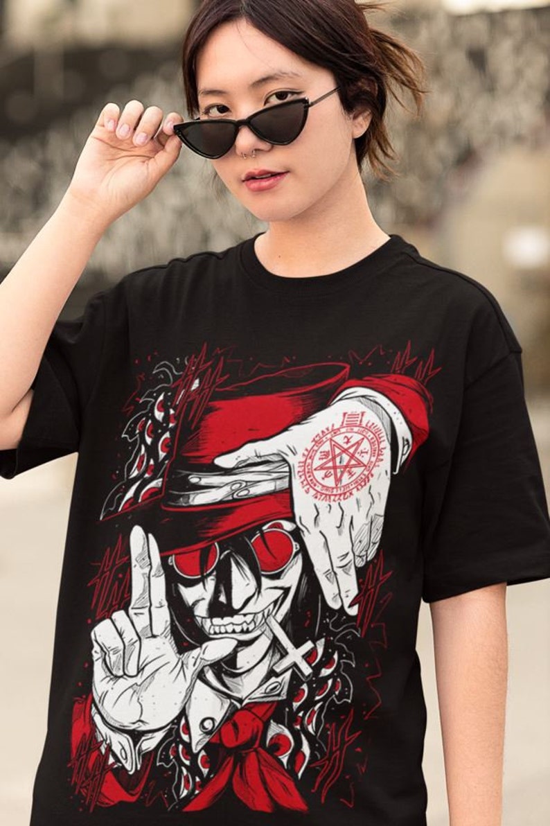 May include: Black t-shirt with a red and white illustration of a vampire with a top hat and a pentagram on his hand. The vampire is wearing a red tie and has a cross on his chest. The background is black with red and white details.