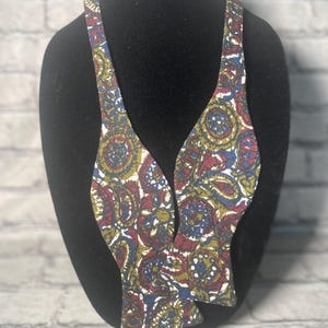 Può includere: Un papillon con un motivo paisley in tonalità di blu, rosso, verde e bianco.