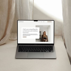 May include: A laptop computer with a website open on the screen. The website has a white background with black text. The text on the website says "Craft your compelling title to showcase your business & services". There is a photo of a woman in the background of the website.