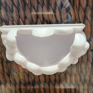 May include: White ceramic planter shaped like a cloud with a rounded opening in the center. The planter is designed to hold small plants or succulents.