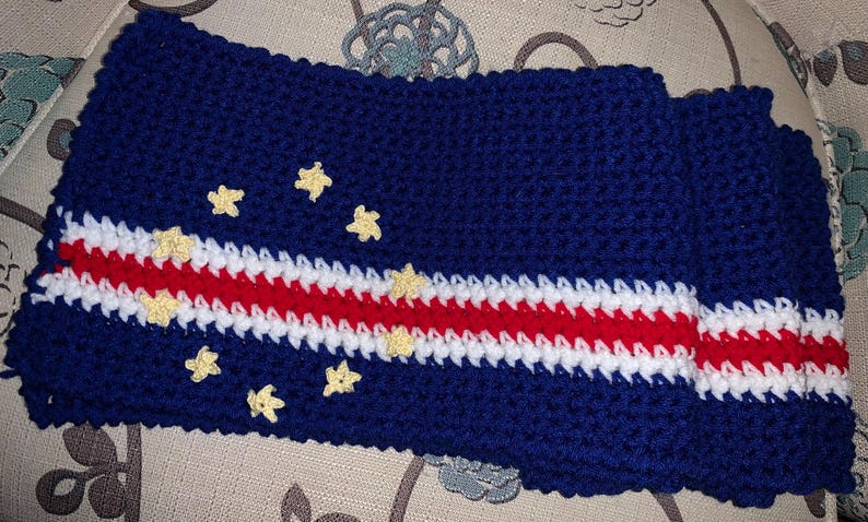 Op de afbeelding: Gehaakte sjaal in de kleuren van de vlag van Kaapverdi&euml;. De sjaal is blauw met een witte en rode streep en gele sterren.