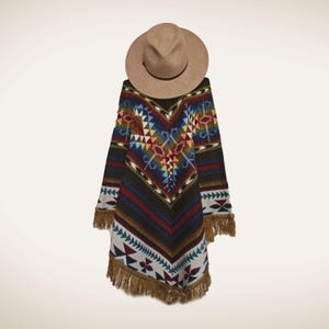May include: A brown fedora hat rests on a colourful poncho. The poncho features a geometric pattern in shades of blue, red, yellow, and white, with brown fringe along the bottom. The poncho is approximately 102 cm long.